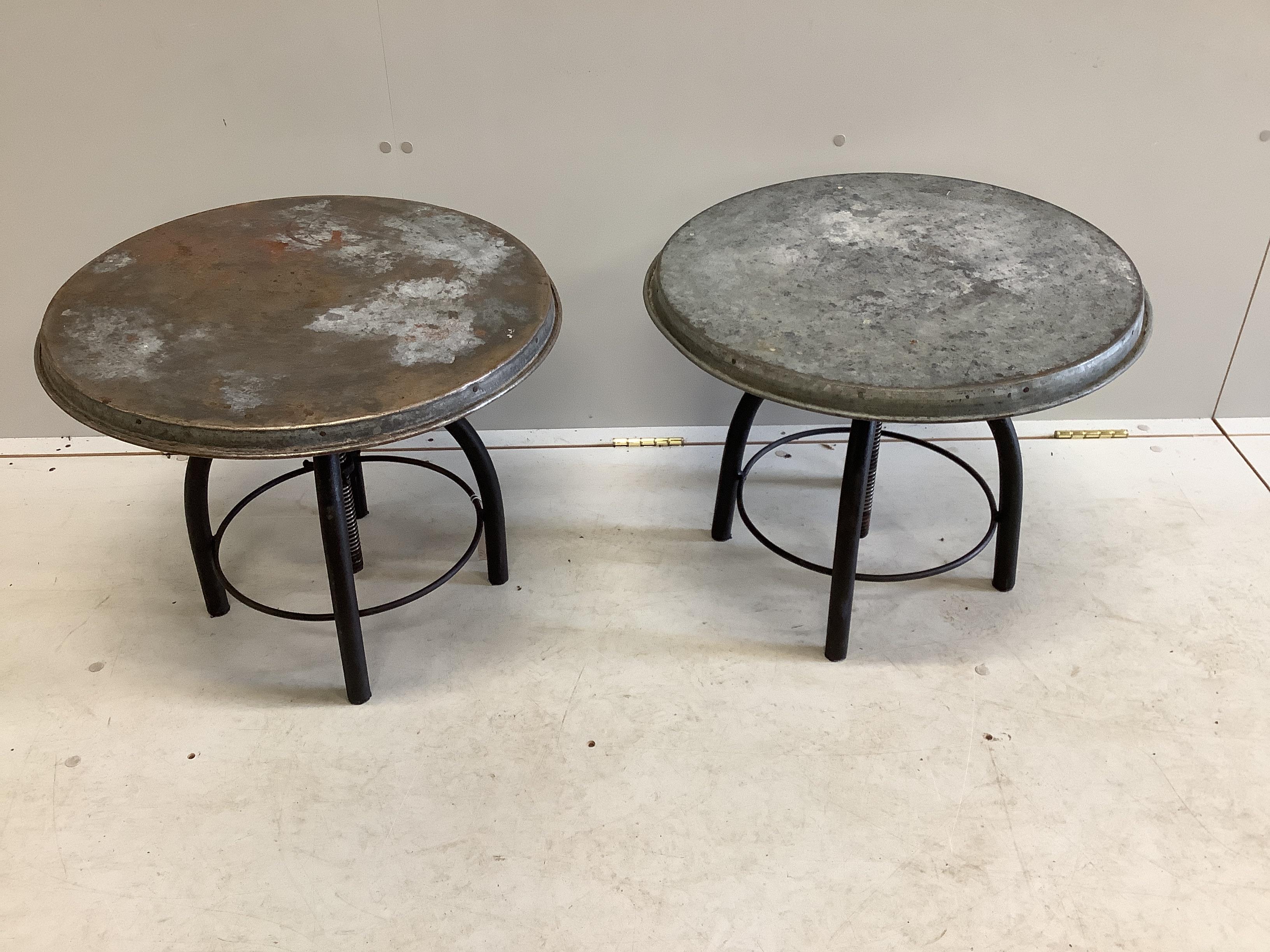 A pair of industrial style circular metal height adjustable occasional tables, diameter 54cm